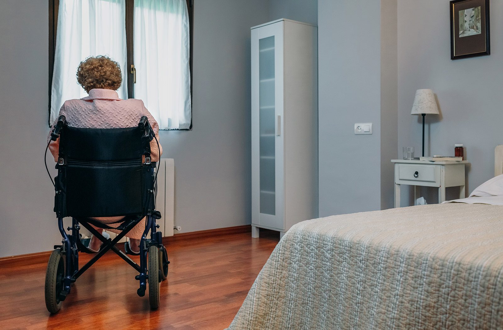 A woman sitting in a wheelchair looking out the window.
