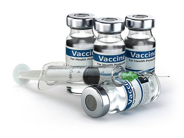 A group of four vaccine bottles and an empty needle.